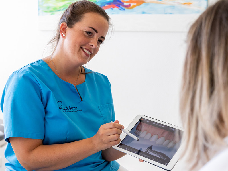 Beratung einer Patientin anhand einer Zahndarstellung auf dem Tablet