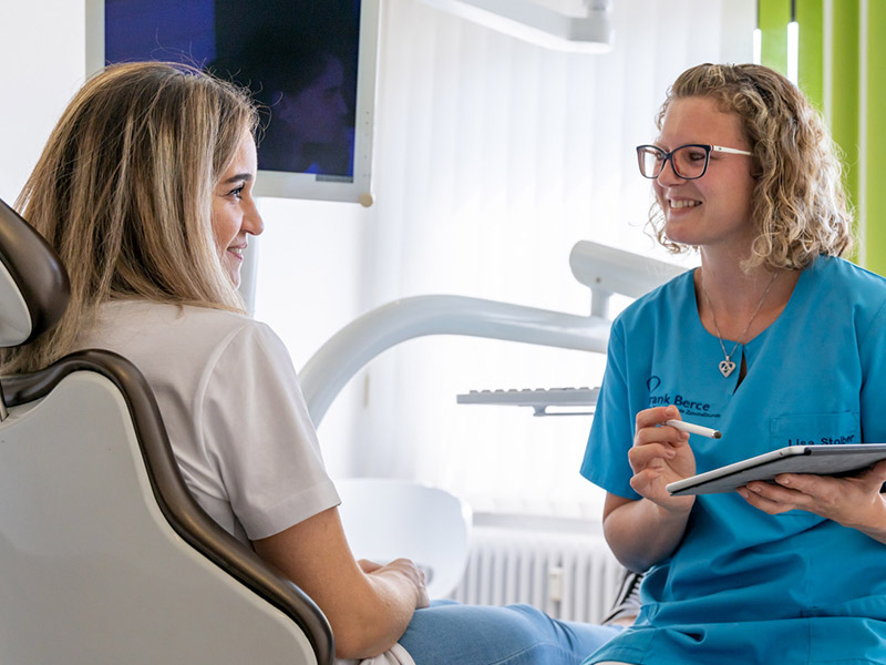 Mitarbeiterin im Gespräch mit einer Patientin am Behandlungsstuhl